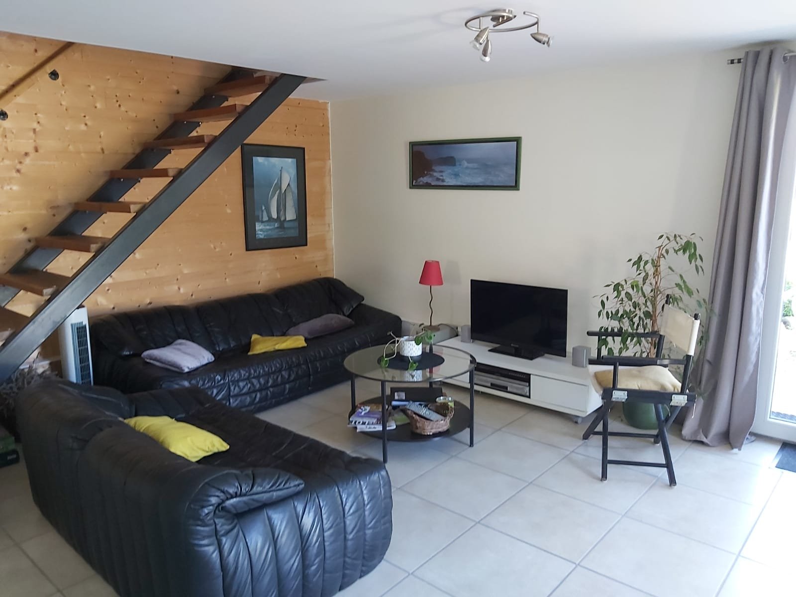 Salon avec canapé en cuir et escalier en bois